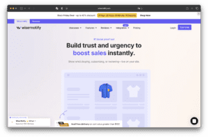 Wisernotifyのウェブサイトのトップページには、信頼構築と売上向上に関する見出し、上部のナビゲーションメニュー、青いシャツの商品画像とオンラインストアのグラフィックが表示されている。.